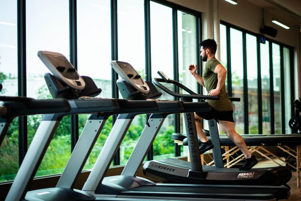 Jeune homme sur un tapis de course dans sa salle de sport